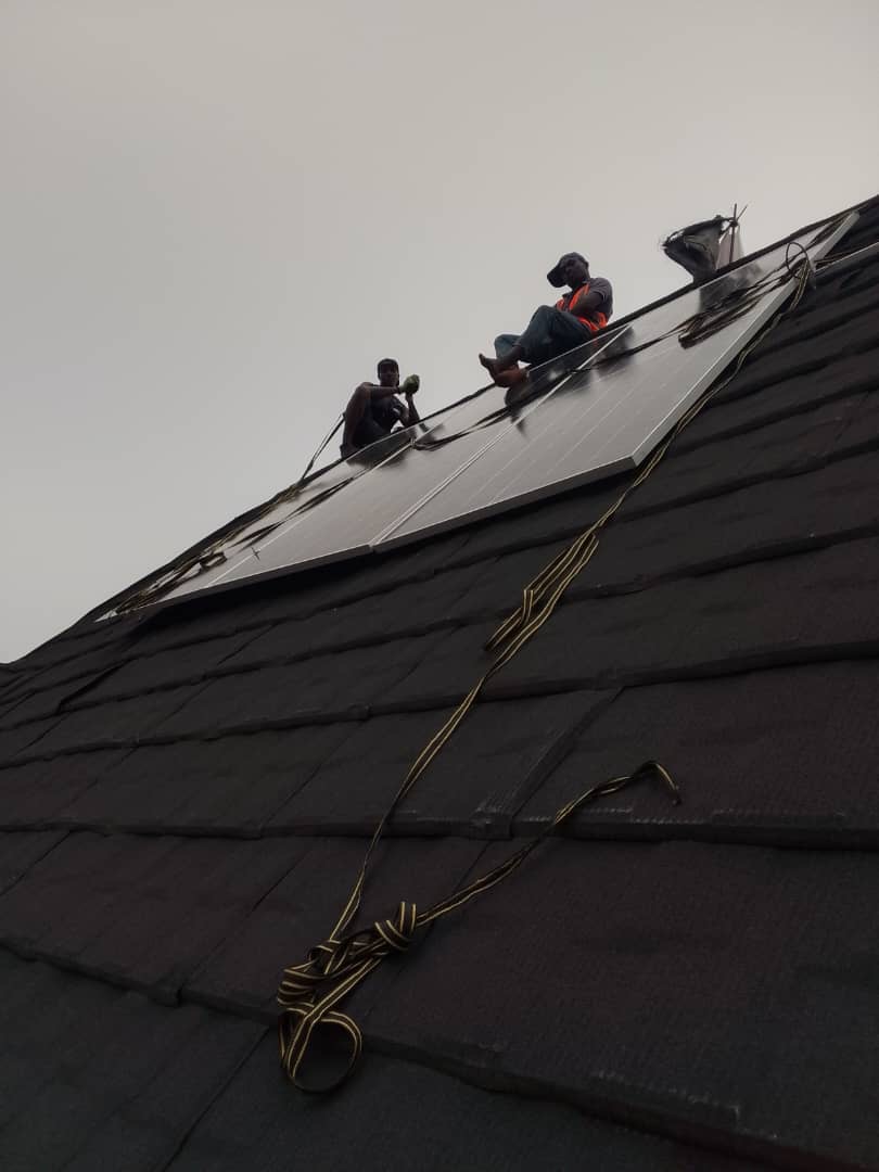 Two engineers mounting a solar panel on a rooftop during installation