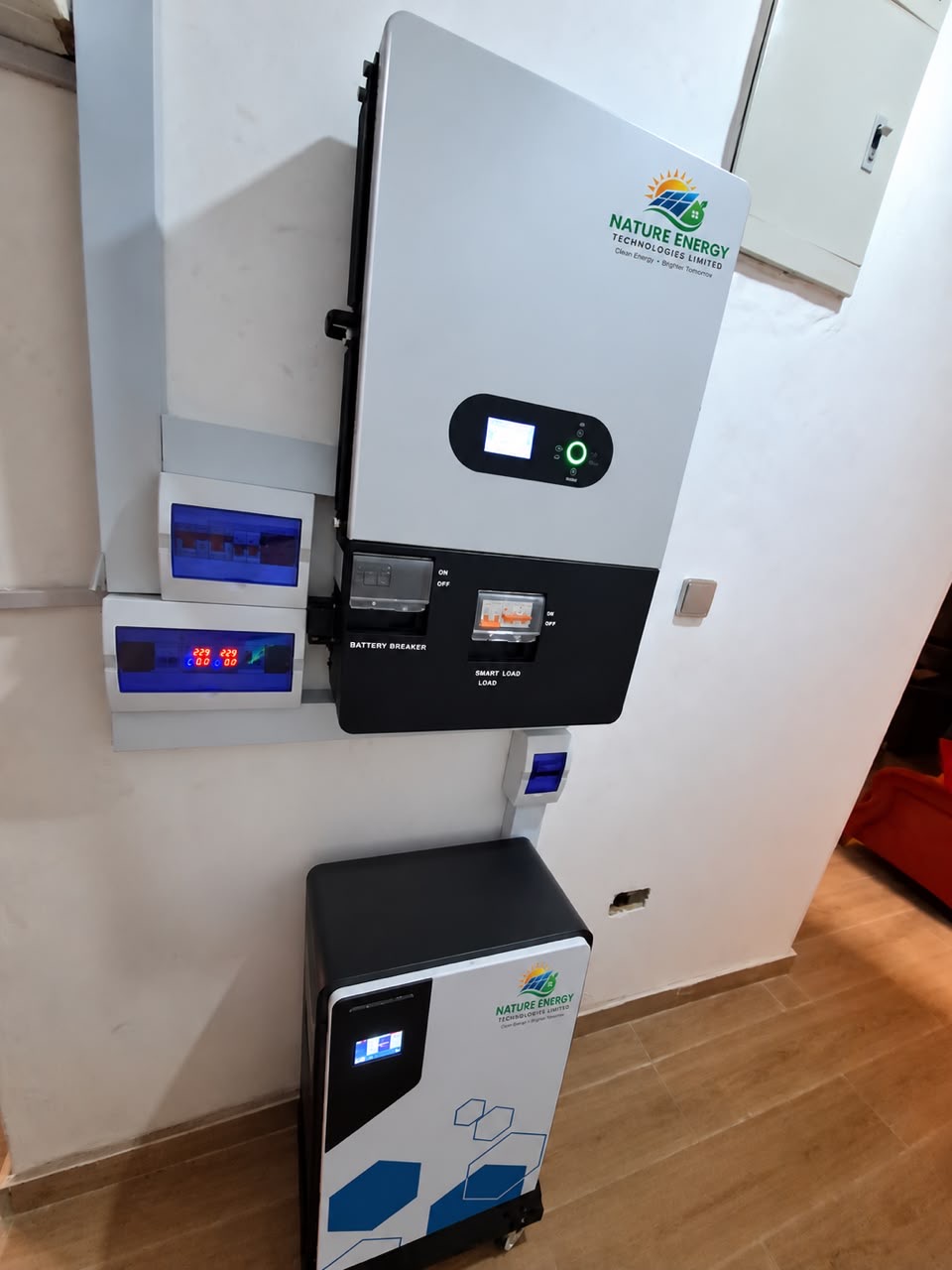 Wall-mounted hybrid inverter with distribution boards and a battery unit below it