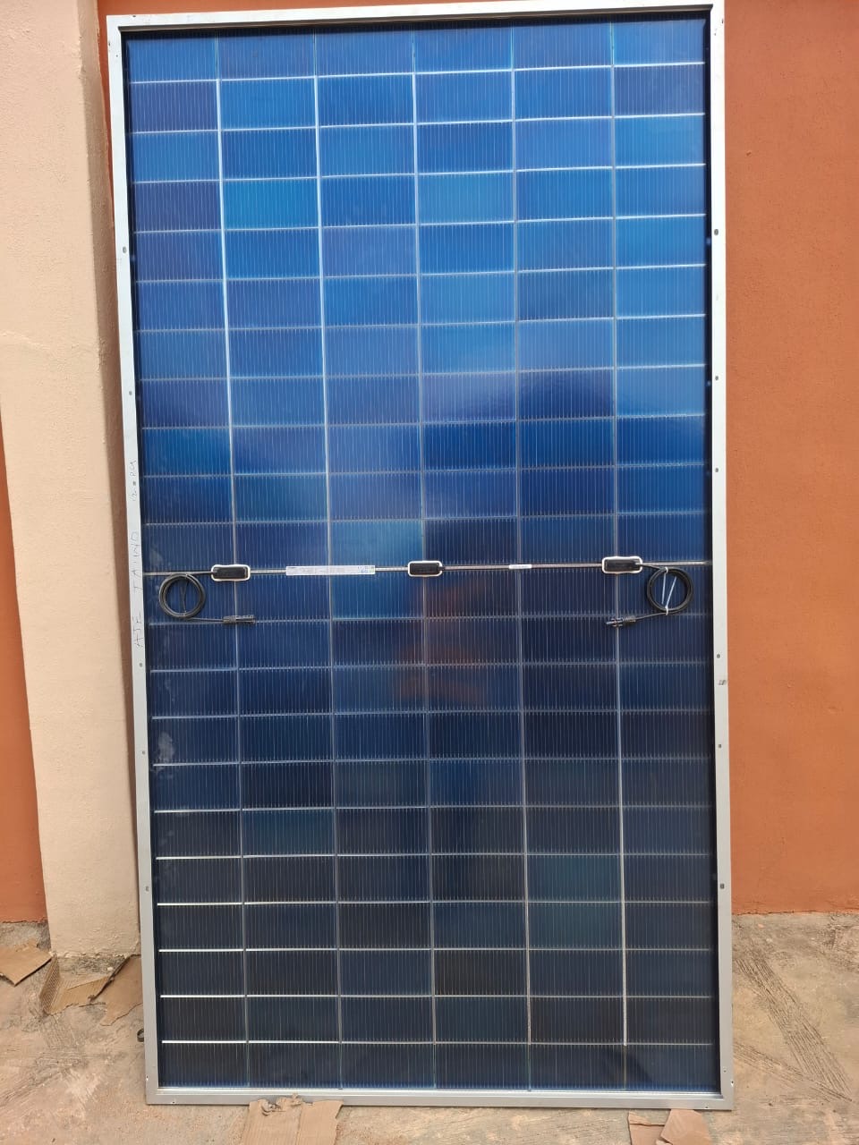 Solar panel standing upright showing its cell grid and aluminium frame